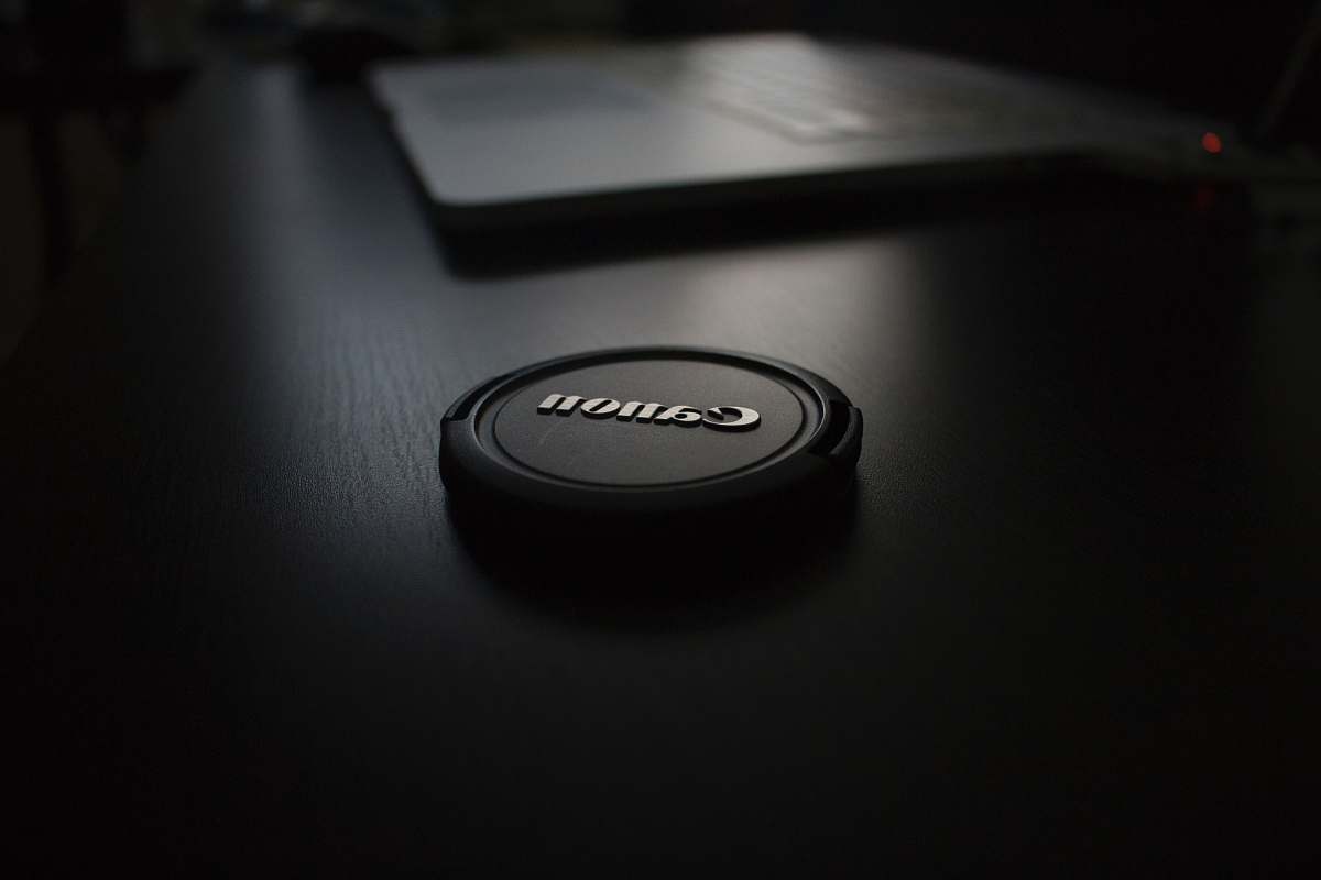lens cap shallow focus photography of black Canon zoom lens cover cap